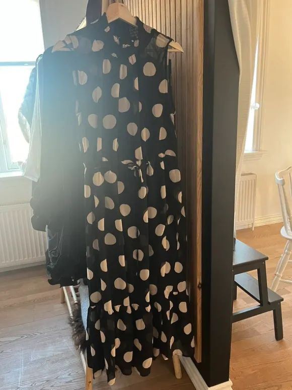 Prikket kjole med flot hals og fast bindebånd i taljen.